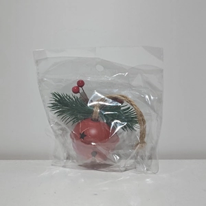 Detail of red Christmas bell ornament with star cutouts, pine needles and red berries