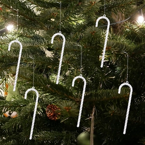 Close-up of glittery silver candy cane ornaments hanging on a lighted Christmas tree