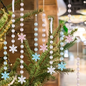 Macro shot of colorful acrylic snowflake pendants on a warm lit Christmas tree branch
