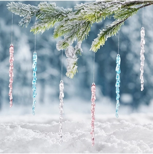 Close-up of pink, blue, and clear acrylic icicle ornaments hanging on snowy pine branches