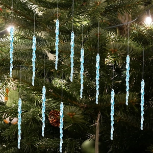 Detail of light blue transparent acrylic icicle ornaments hanging on a Christmas tree