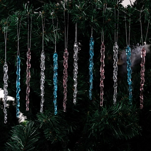 Transparent, blue, and pink acrylic icicle ornaments on a Christmas tree branch