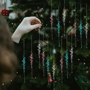 Acrylic Christmas icicle ornaments in clear, pink and blue hanging on a tree