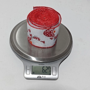 Macro shot of a red and white Christmas ribbon roll on a scale weighing 62.7g