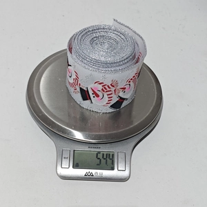 Detailed view of white Christmas ribbon with snowman print and silver glitter edges on a scale
