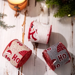 Λεπτομέρεια από λινές κορδέλες με τύπωμα HO HO HO σε ξύλινο δάπεδο με πεύκο και ζεστά φώτα