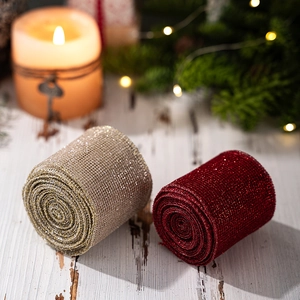 Detail showing red and gold mesh ribbon rolls on wood with warm festive decor