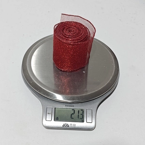 Close-up of a 21.3g roll of red mesh Christmas ribbon on a scale for weight display