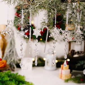 Nahaufnahme von klaren Acryl-Weihnachtsanhängern an einem Tannenbaum mit warmem Licht