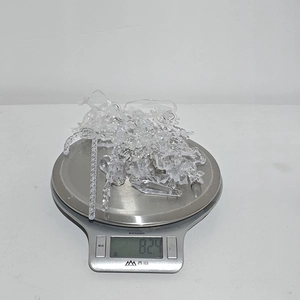 Makroaufnahme von 8 Stück Acryl-Weihnachtsanhängern mit einem Gewicht von 82,4g auf einer Waage