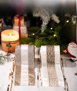 Close-up of golden Christmas ribbons and white mesh on vintage wood with warm lights