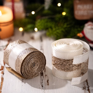 Detail of luxury gold Christmas ribbons on wood with festive pine and warm bokeh light