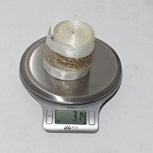 Detailed view of 31.4g gold and white glitter mesh Christmas ribbon on a scale