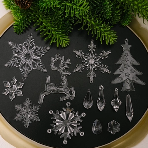 Set aus klaren Acryl-Weihnachtsanhängern mit Rentieren und Schneeflocken auf dunklem Tablett