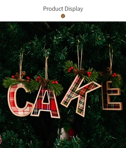 Detail of CAKE letter Christmas ornaments with red plaid and pine needles on a tree