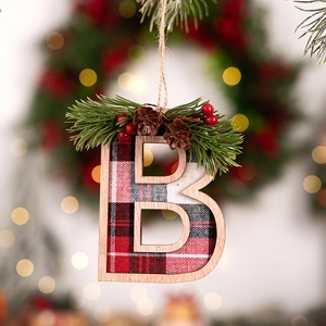 Detail of wooden letter B ornament with red plaid fabric, pine needles, and pine cones