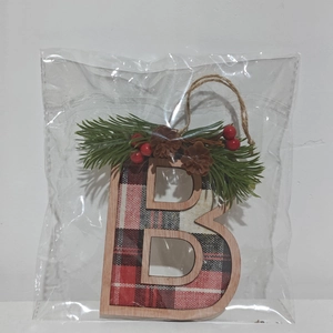 Detail of wooden letter B Christmas ornament with red black plaid fabric and pine needles
