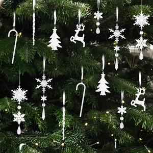 Détail des ornements de flocon de neige et renne en acrylique blanc sur un sapin