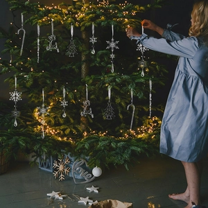 Détail de rennes et flocons en acrylique transparent suspendus au sapin de Noël illuminé