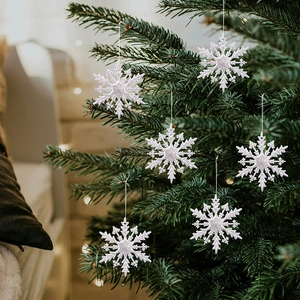 Gros plan de flocons de neige blancs pailletés suspendus sur un sapin de Noël avec effet bokeh