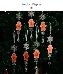 Close-up of acrylic gingerbread man and snowflake ornament on a green Christmas tree