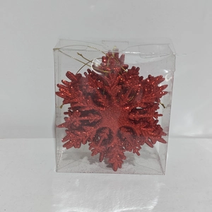 Gros plan d'un flocon de neige à paillettes rouges dans sa boîte plastique carrée