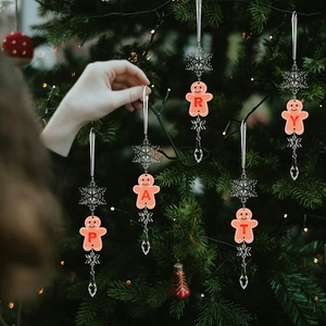 Close-up of pink gingerbread man pendants with PARTY letters on a Christmas tree