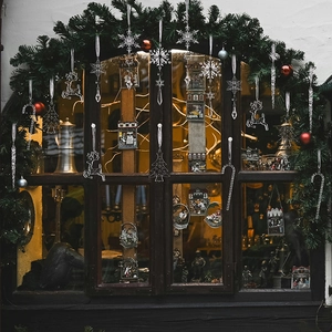 Clear acrylic Christmas ornaments hanging on a window with warm festive lighting
