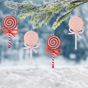 Detail of glittery Christmas lollipop ornaments with bows hanging on snowy pine branches
