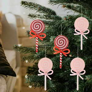 Close-up of glittery red and pink candy lollipop ornaments with bows on a Christmas tree
