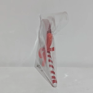 Macro view of a red spiral candy ornament featuring a sparkling glitter bow in its packaging
