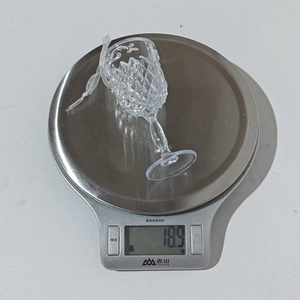 Primer plano de un colgante de campana de ángel acrílico transparente de 18,9 g en una báscula