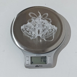 Foto macro de campana navideña de acrílico transparente pesando 17g en báscula digital