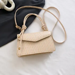 Mini borsa beige a pieghe con manico annodato vicino allo smartphone per scala dimensionale