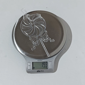 Detalle de un adorno de piruleta acrílica transparente de 19,3 g en una báscula
