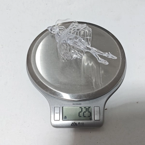 Adorno navideño de bailarina de acrílico transparente mostrando un peso de 22,5g en la báscula