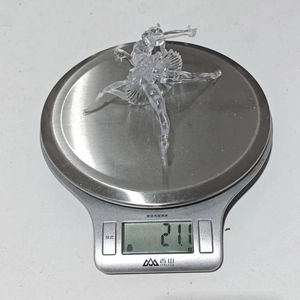 Medición del peso de una bailarina de acrílico transparente que marca 21,1g en la báscula