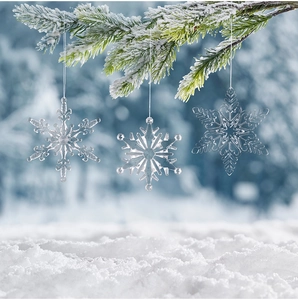 Detailed view of clear acrylic snowflake ornaments hanging on snow-covered pine branches
