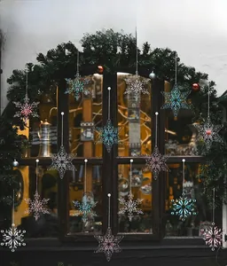 Hanging acrylic snowflake ornaments in clear pink and blue on a festive window display