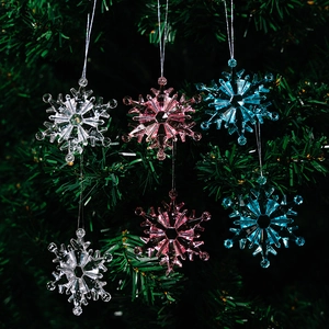 Close-up of clear acrylic snowflake ornaments in pink and blue on Christmas tree