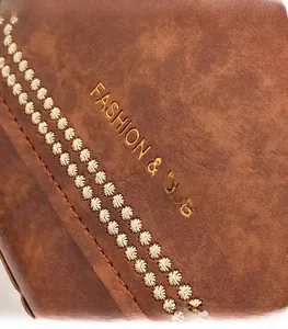 Détail d'un sac en cuir marron vintage avec broderie florale et logo doré