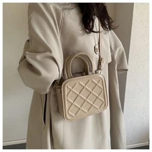 Détail du sac bandoulière matelassé beige montrant la texture cuir et la poignée