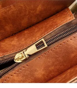 Détail macro d'une fermeture éclair en métal doré sur un sac bandoulière en daim brun