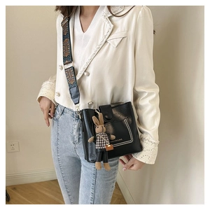 Détail du sac seau noir en cuir avec rivets et bandoulière large de style ethnique