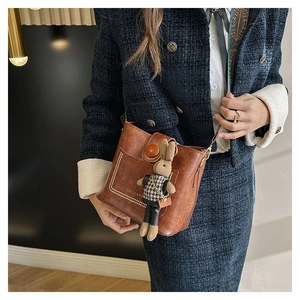 Vue détaillée du sac seau marron en cuir avec coutures blanches et breloque lapin