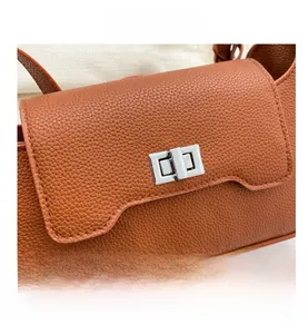 Close-up of orange-brown litchi pattern leather bag with silver rectangular metal twist lock