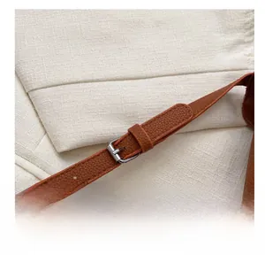 Close-up of caramel leather strap with silver adjustable buckle and lychee texture