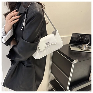 Detail of white lychee pattern leather shoulder bag with silver metal lock on a black coat