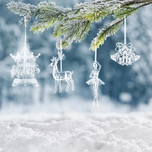 Set de cuatro adornos navideños de acrílico transparente colgados en una rama de pino nevada