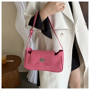 Pink lychee grain leather underarm bag with silver turn-lock clasp shown on shoulder